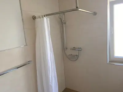 Große, barrierefreie Dusche im hellen Badezimmer