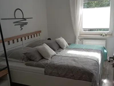 Doppelbett mit zwei einzelnen Matratzen, offenem Kleiderschrank und Nachttischschränken