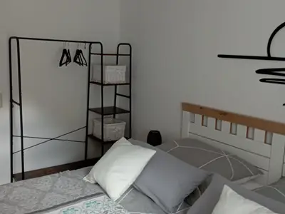 Schlafzimmer mit Doppelbett sowie einem offenen Kleiderschrank
