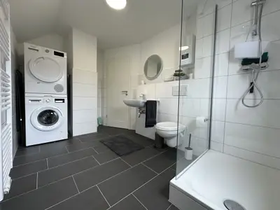 helles, modernes Badezimmer mit Glasdusche, Waschmaschine und Trockner