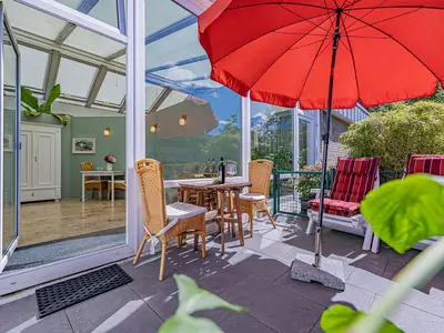 Sonnige Terrasse mit Gartenmöbeln und Sonnenliegen