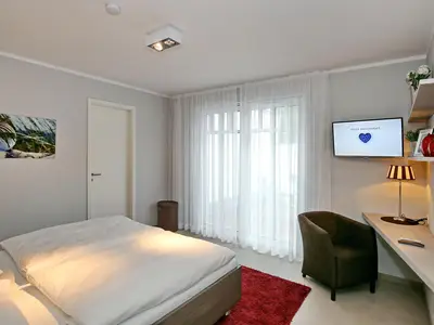 Schlafzimmer mit Doppelbett und TV