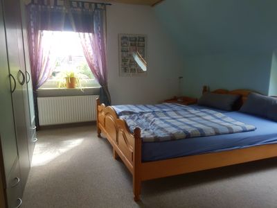 Schlafzimmer mit Doppelbett und zusätzlichem Bett hinter Raumteiler