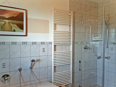 Badezimmer mit Dusche, Badewanne und Waschmaschine