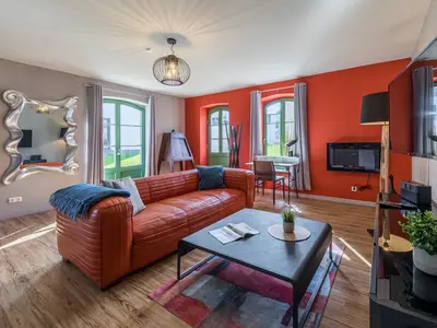 Ferienwohnung Müritzperle Klink Wohnzimmer mit rotem Sofa und modernem Spiegel
