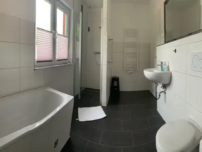 großes Bad mit ebenerdiger Dusche, Badewanne, Handtuchhalter und Waschmaschine