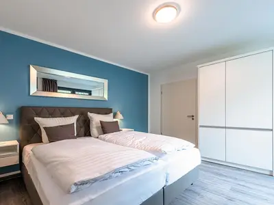 Apartment K15 Tao-Suite Krakow – ruhiges, modernes Schlafzimmer mit komfortablem Doppelbett, türkisfarbener Akzentwand