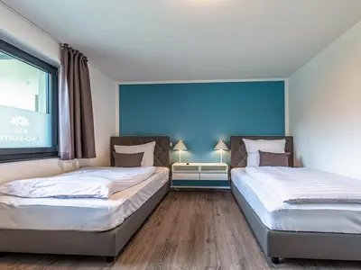 Apartment K15 Tao-Suite Krakow – ruhiges Schlafzimmer mit zwei komfortablen Einzelbetten und türkisfarbener Akzentwand