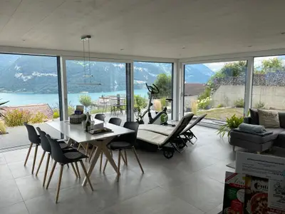 Essraum mit Liegestühle für draussen und drinnen mit grosser Glasfront und traumhaftem Ausblick auf Berge und Thunersee