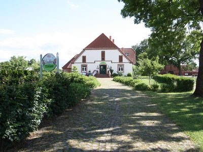 Außenansicht des Gebäudes. Auffahrt zum Haus,hinter der Hecke befindet sich der Parkplatz