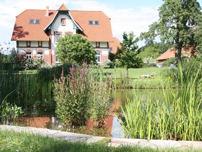 Garten. Teil des Schwimmteichs mit Jugendstilhaus im HIntergrund