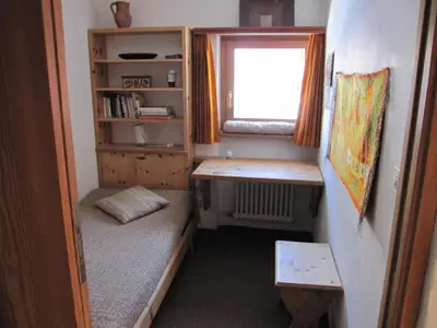 Im Schlafzimmer befindet sich ein Bett mit Bettzeugtruhe sowie ein Klapptisch mit Hocker und ein Arvengestell.