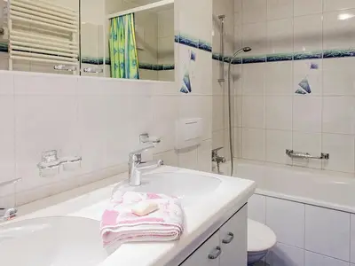 Badezimmer mit Doppelwaschtisch und Badewanne