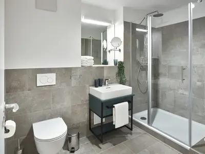 Badezimmer mit Dusche, Waschtisch, WC und Spiegel