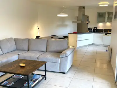 Salon mit grossem Sofa und offener moderner Küche