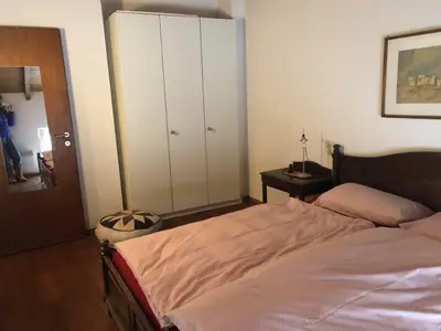 Geräumiger Wandschrank, Spiegel, Nachttisch mit Lampe neben dem grossen Bett.