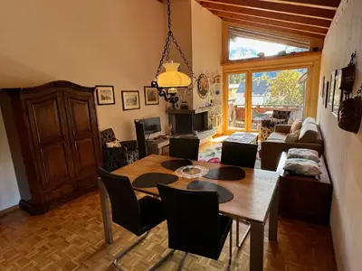 Wohnraum mit Kamin und Balkon zur Südseite mit Sicht auf die Berge