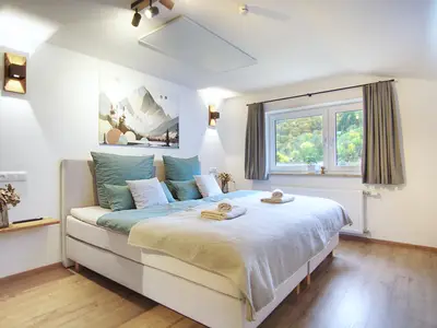 Schlafzimmer mit bequemem Boxspringbett, TV und Infrarotheizung, Blick auf Terrasse