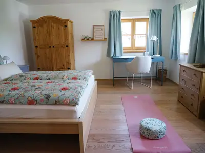 Freundliches Schlafzimmer mit Schreibtisch und Yogamatte