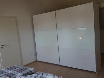 großer Kleiderschrank, der auch als Raumteiler für das Zusatzbett dient 