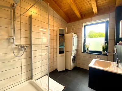 Badezimmer mit Dusche, WC, Waschmaschine und Trockner.