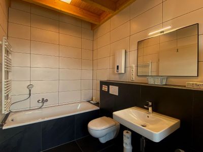 Badezimmer mit WC, Badewanne sowie Waschmaschine und Trockner.