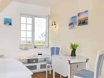 Der Bereich zwischen Bett und Esstisch in der Ferienwohnung Wattstübchen in Norddorf auf Amrum