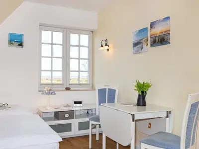 Der Bereich zwischen dem Doppelbett und dem Esstisch in der Ferienwohnung Wattstübchen in Norddorf auf Amrum