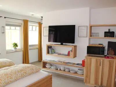 Blick von Sitzecke in den Raum mit Doppelbett, TV und privatem Gartenbereich