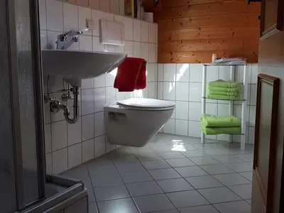 Badezimmer mit Dusche und WC, Haartrockner, Toilettenartikel und Pantoffel