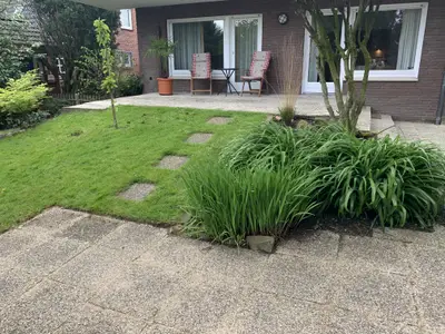 Hinterseite des Hauses mit grünem Garten und Sitzflächen