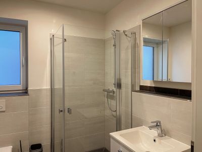 Badezimmer mit ebenerdiger Dusche und beleuchtetem Spiegelschrank