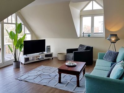 Wohnzimmer mit Sofa, Sessel und TV