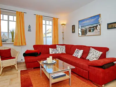 Wohnzimmer mit Schlafcouch und Korbsessel