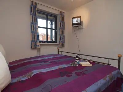 Schlafzimmer mit Doppelbett und TV