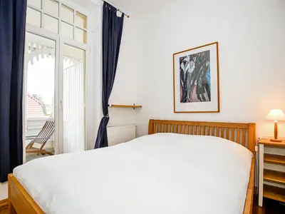 Schlafzimmer mit Doppelbett und Zugang zum Balkon