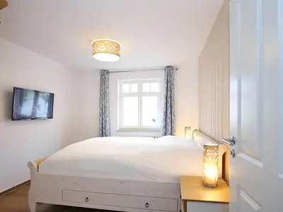 Schlafzimmer mit Doppelbett und TV