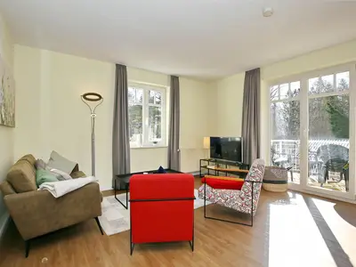 Wohnzimmer mit Sofa, Sesseln und TV