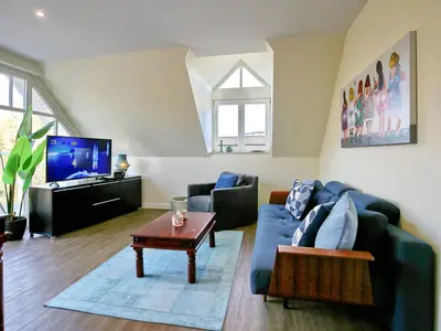 Wohnzimmer mit Sofa, Sessel und TV