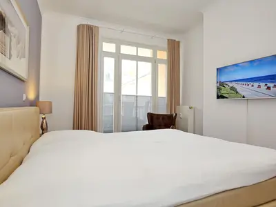 erstes Schlafzimmer mit Boxspringbett und TV