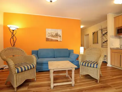 Wohnzimmer mit Schlafcouch und Korbsesseln