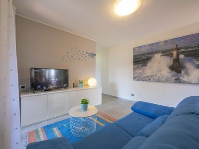 Wohnzimmer mit Schlafsofa, Smart-TV und Zugang zum Balkon