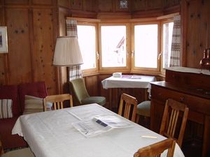 Wohnzimmer mit traditionellem Arventäfer und grossem Tisch, Erker mit herrlicher Aussicht