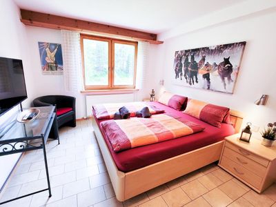 Schlafzimmer Nr.1: großes Doppelbett für 2 Erwachsene, Kleiderschrank, TV, Schminktisch, Sessel und Fenster mit Rolladen