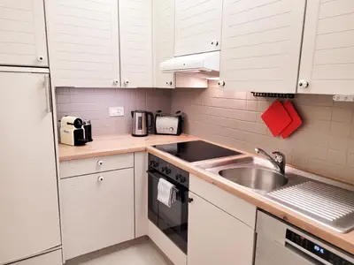 Eine voll ausgestattete Küche mit Waschmaschine, Backofen, Herd, Nespresso-Kaffeemaschine und Milchschäumer.