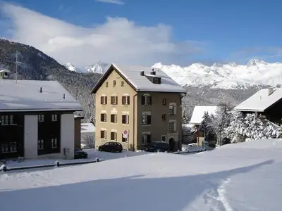 Aussenansicht Winter - Chesa Nadig von Osten, von der Languard-Wiese mit direktem Zugang zur Schlittelwiese/Piste