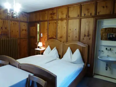 Zimmer 1, geräumig, zwei Betten, Waschgelegenheit, Chaiselongue, Tisch, zwei Stühle, Kasten, Aussicht auf Piz Palü