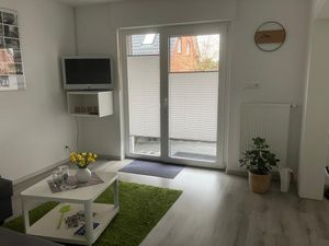 Der helle Wohnraum mit TV und Eingangstür zur Terrasse