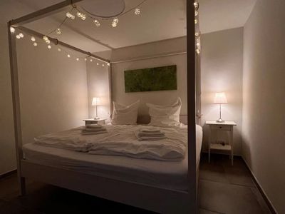 Kuscheliges Doppelbett im Schlafzimmer mit Lichterkette