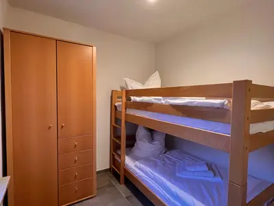 Etagenbett mit Holzschrank in einem der Schlafzimmer